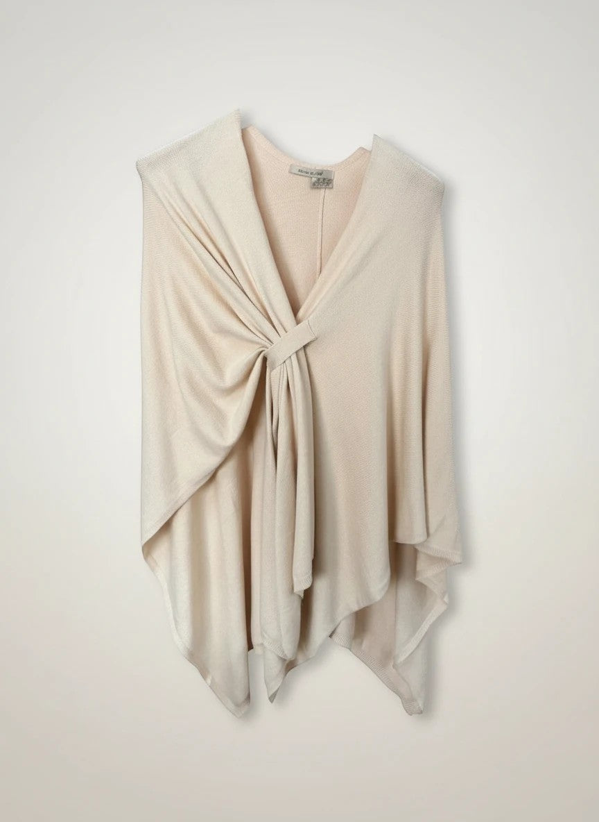 Color's Wholesale beige knit poncho with a knotted front detail and asymmetrical hem.