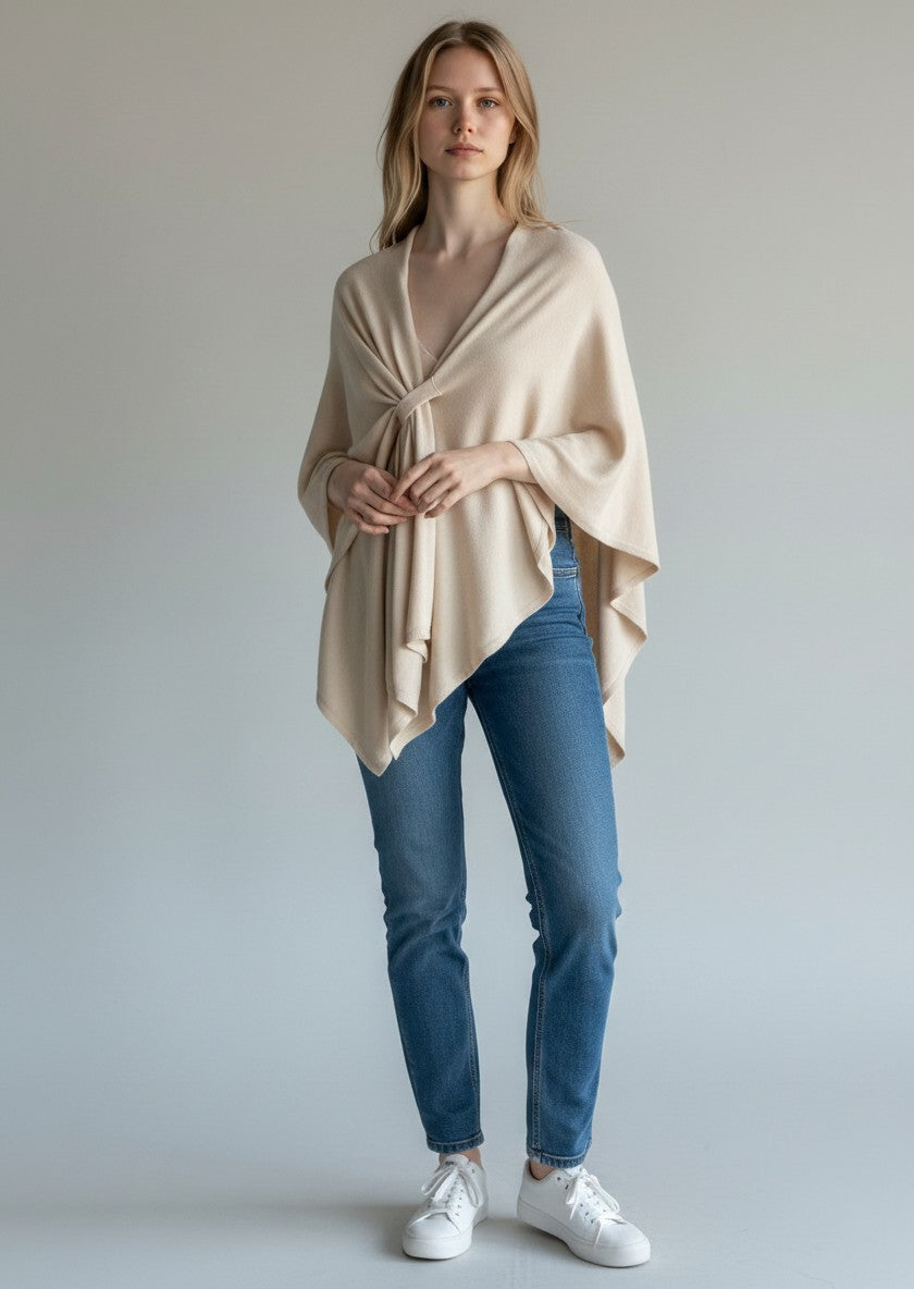 Color's Wholesale beige knit poncho with a knotted front detail and asymmetrical hem.