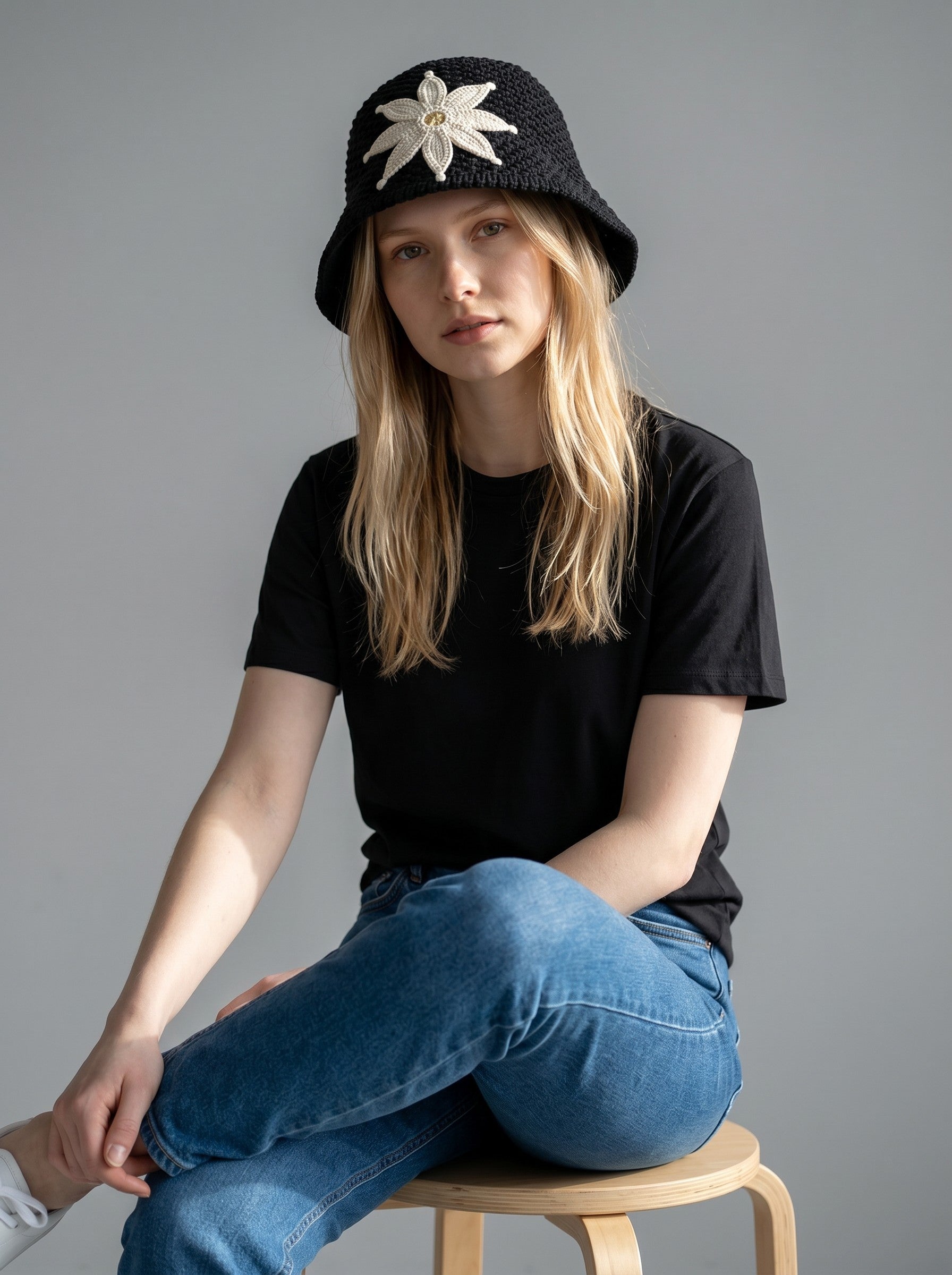 Color's Wholesale black crocheted bucket hat with a cream flower appliqué and beige center.