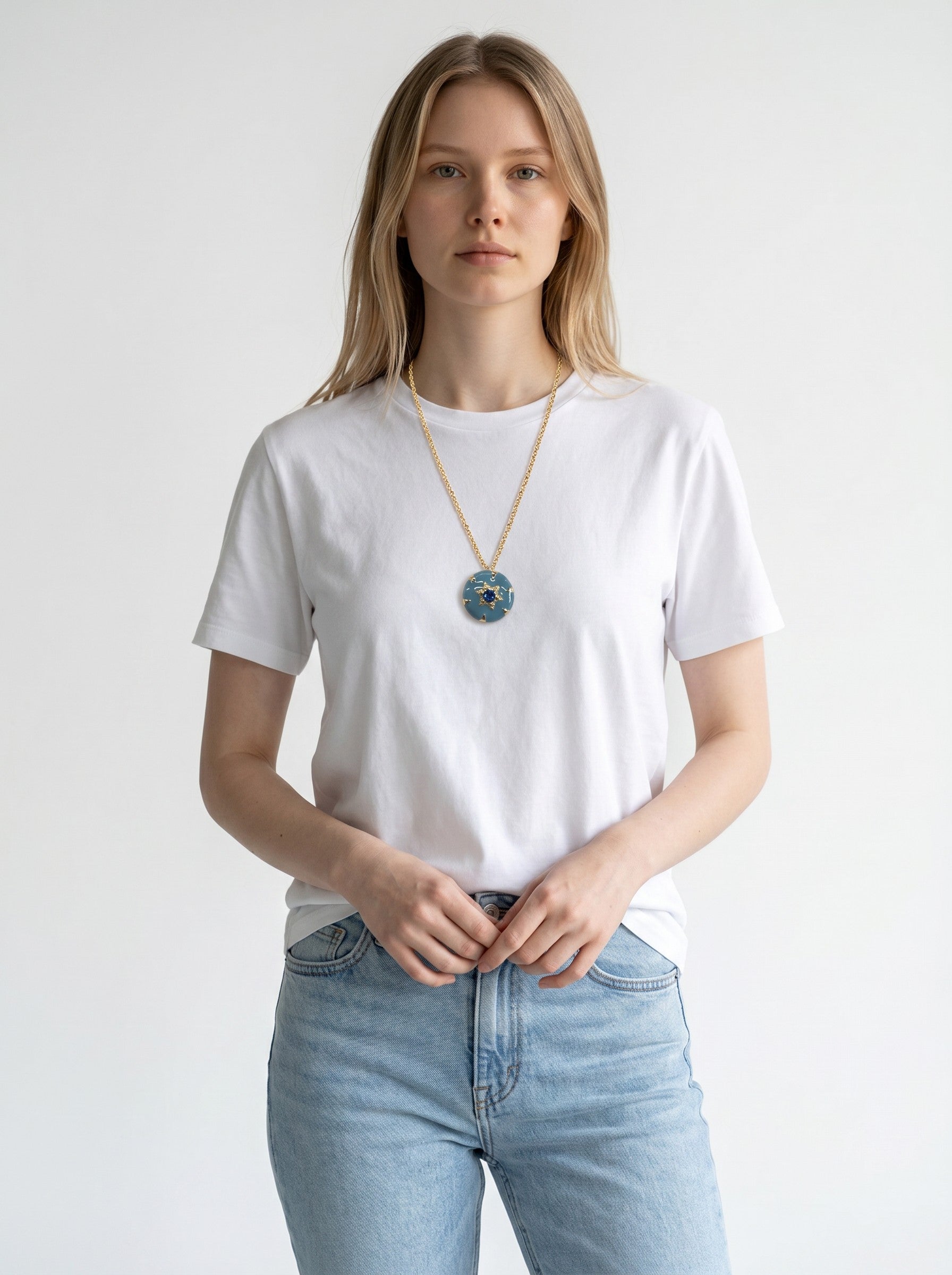 Model wearing a Color's Wholesale gold chain necklace with a round blue pendant featuring gold accents