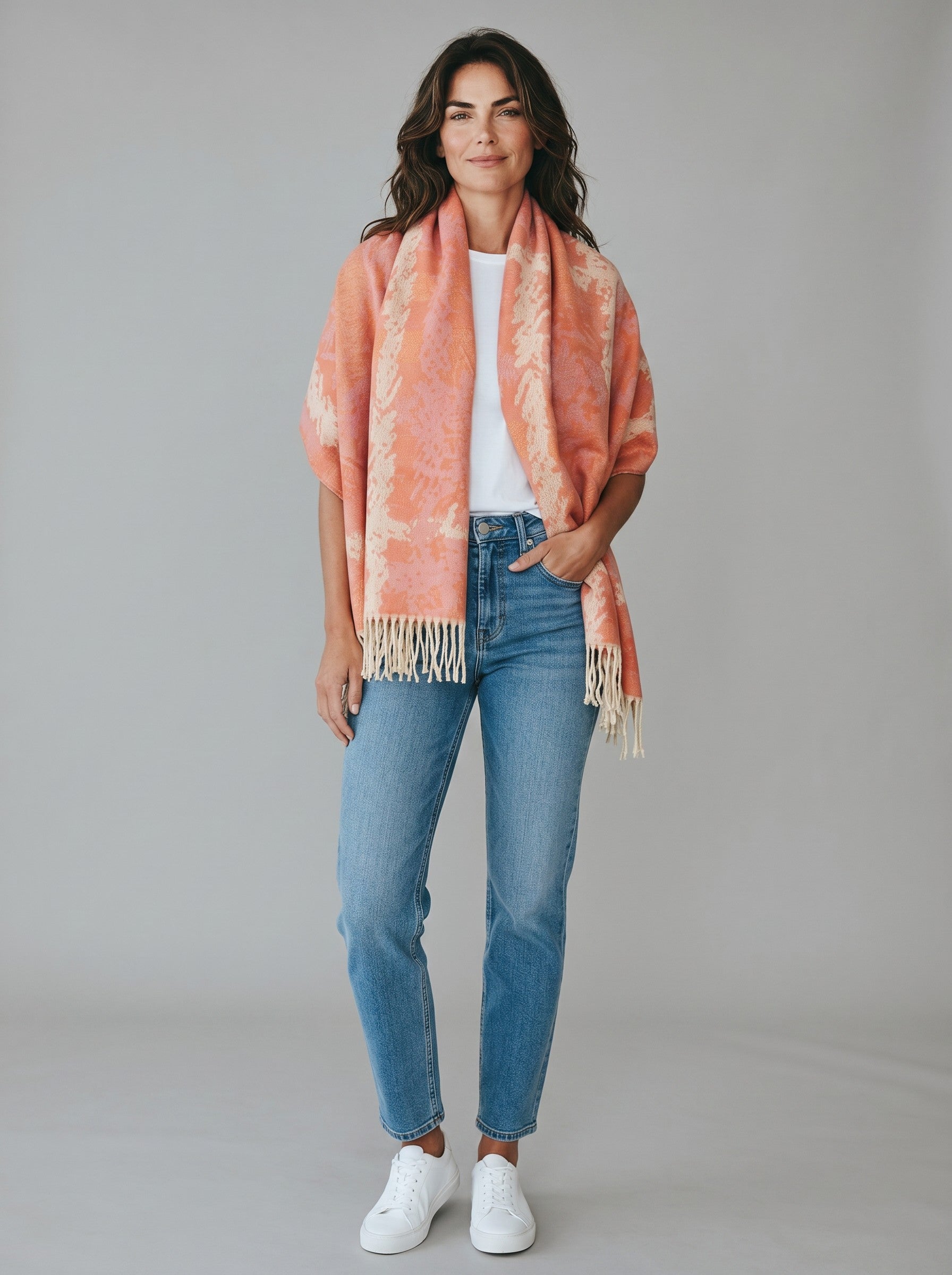 Color's Wholesale viscose scarf in coral and cream tie-dye pattern with fringe trim worn by a woman