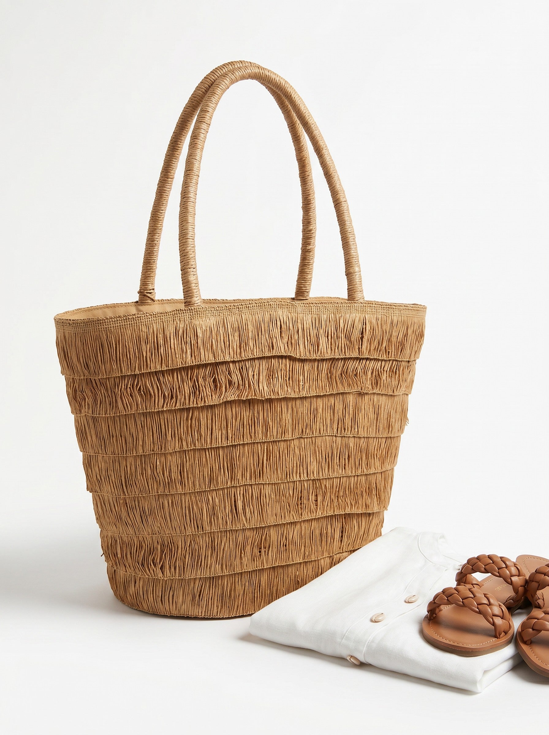 Color's Wholesale Eloise straw tote bag with fringe detail and double handles. Natural straw material.