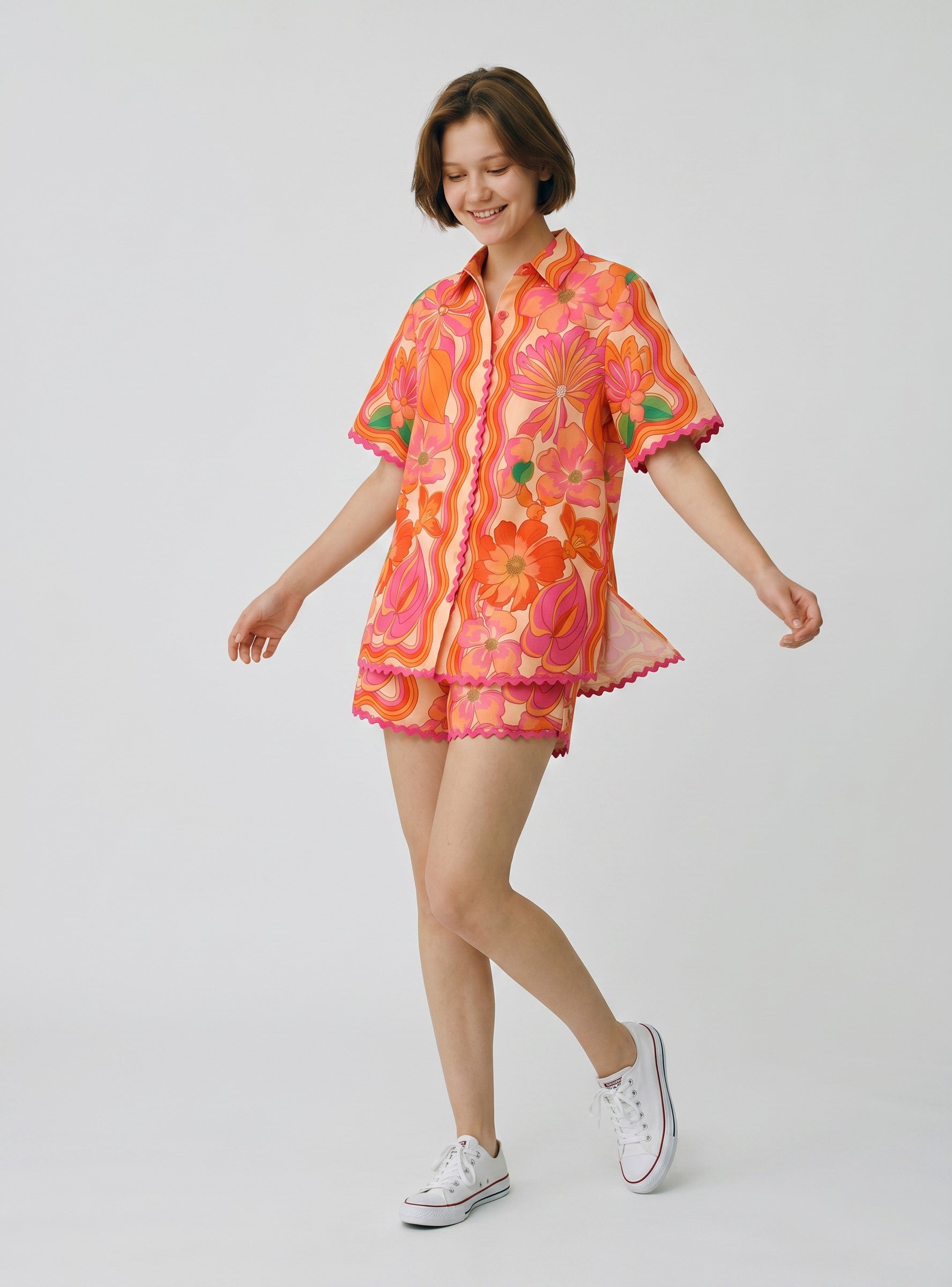 Color's Wholesale women's short sleeve collared shirt and shorts set in a vibrant floral print with pink and orange hues. Made of 65% linen, 35% polyester.