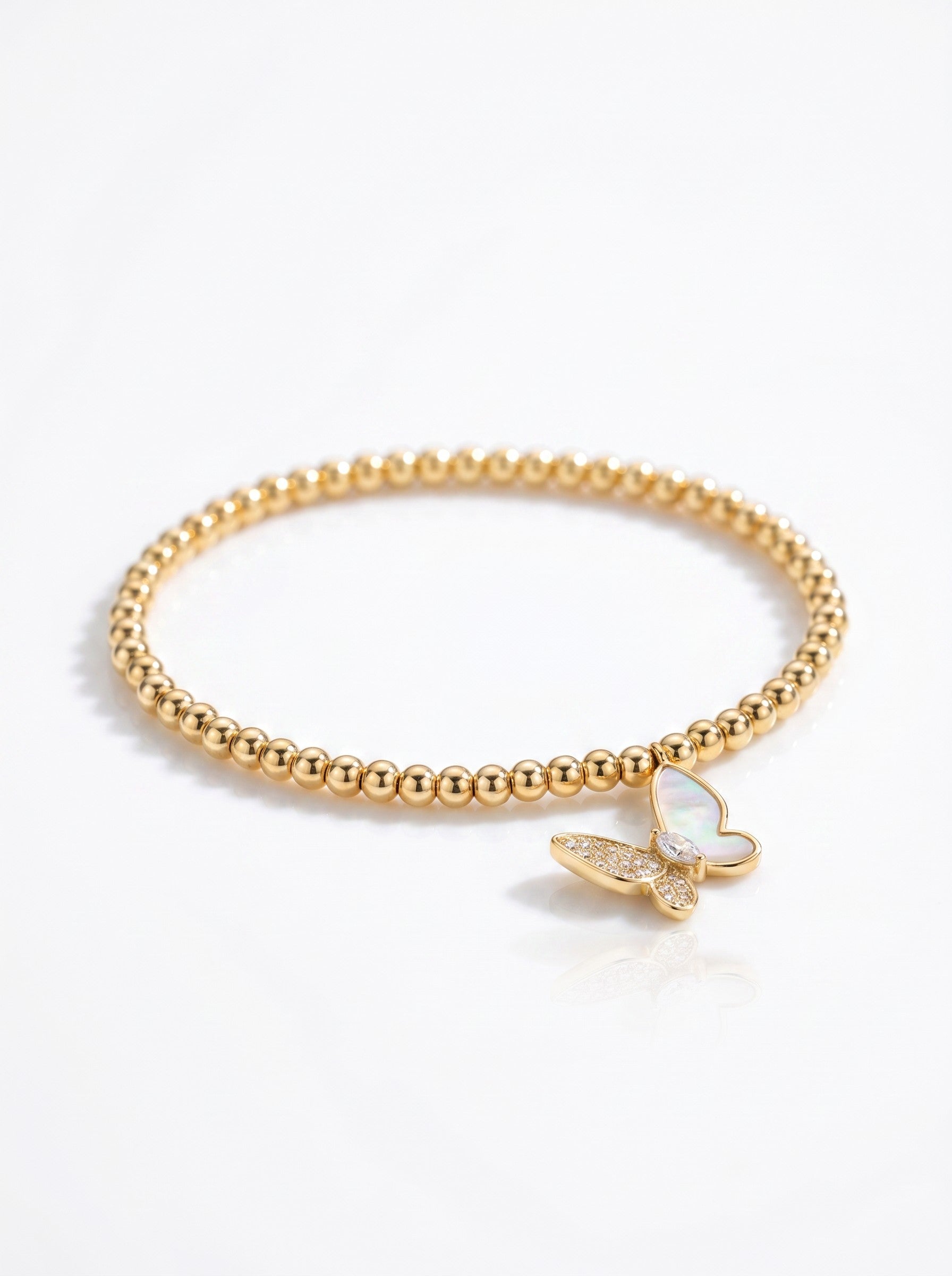 Color's Wholesale gold beaded stretch bracelet featuring a delicate butterfly charm with mother of pearl and crystals.