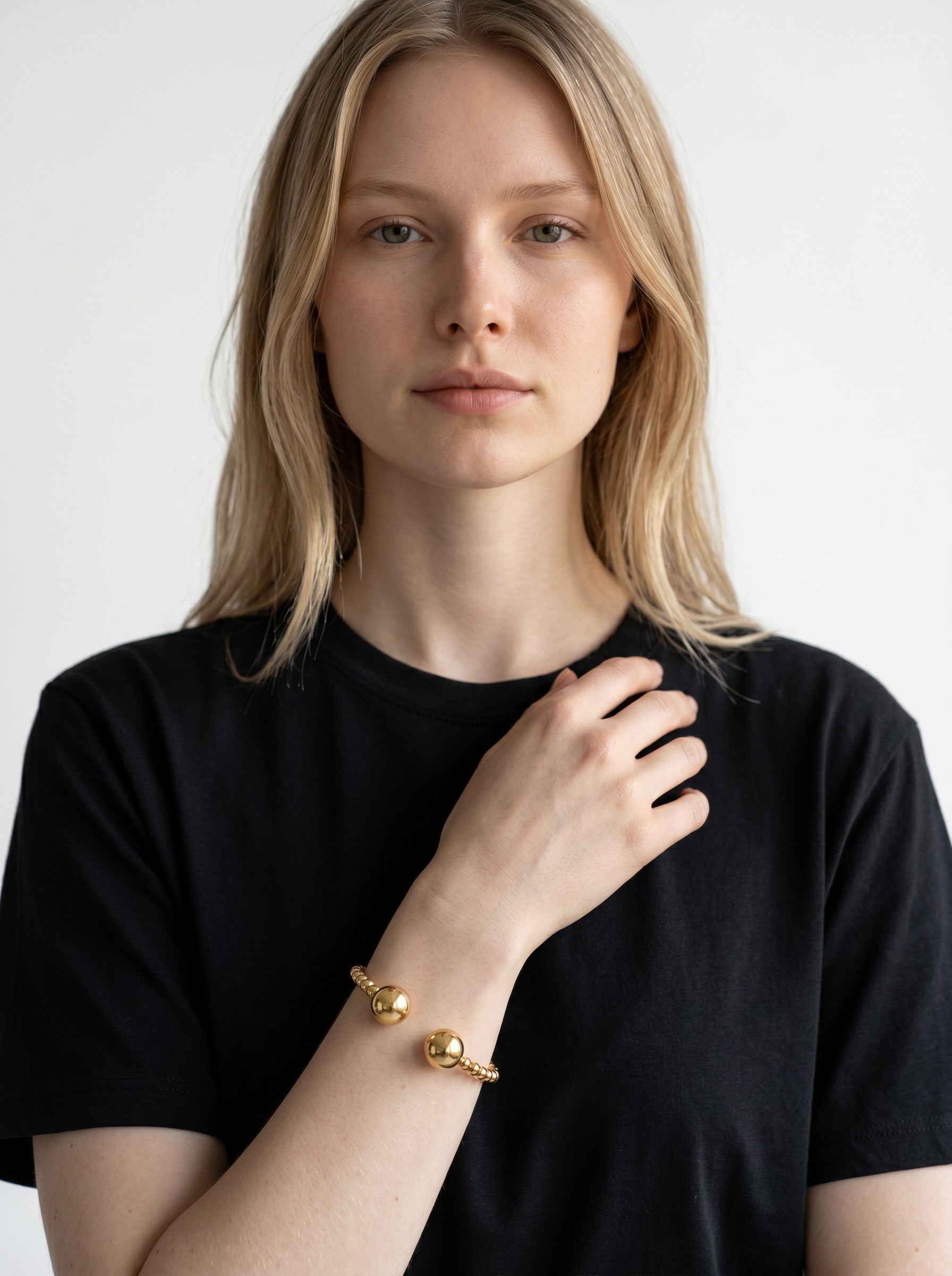 Color's Wholesale gold beaded cuff bracelet with large spherical charms worn on a model in a black t-shirt.