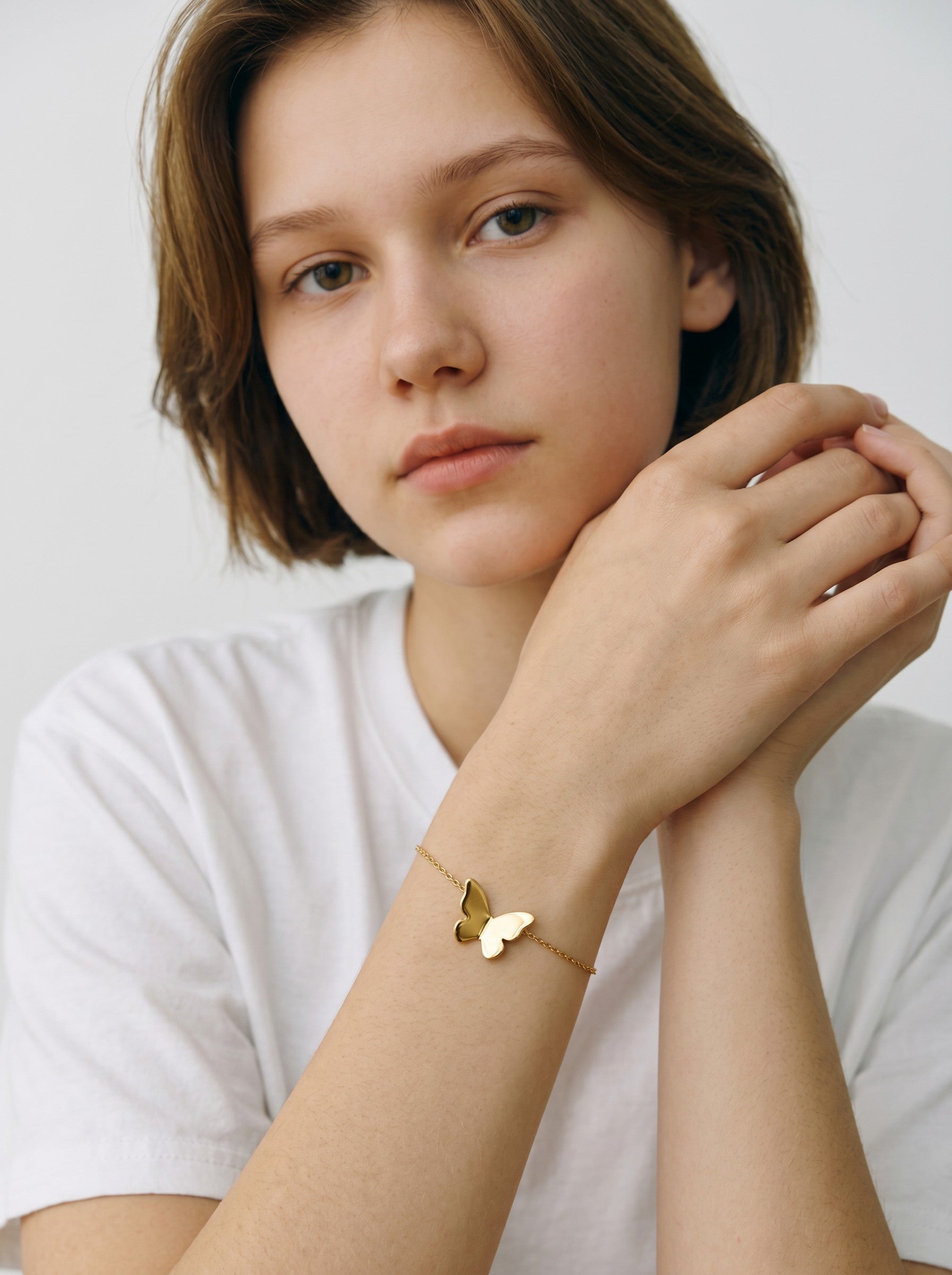 Color's Wholesale gold butterfly charm bracelet worn on a woman's wrist against a simple white background.