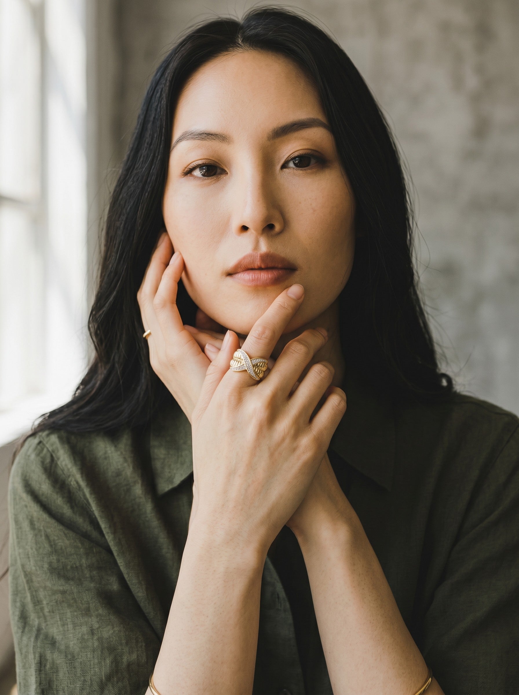 Color's Wholesale gold crossover ring with pave diamonds worn by a woman in an olive green linen shirt