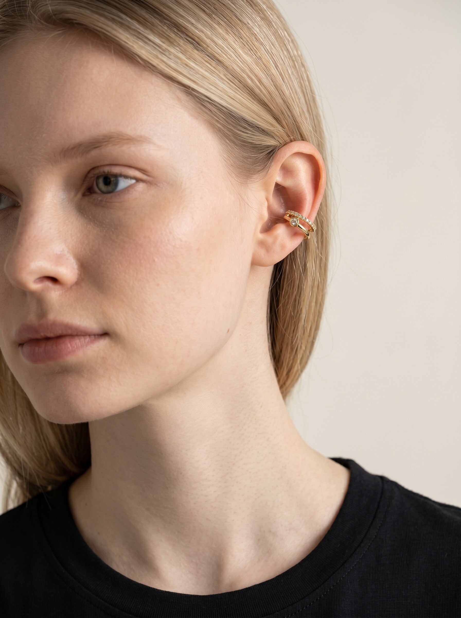 Color's Wholesale gold double-band ear cuff with sparkling pavé crystals worn on a model's ear