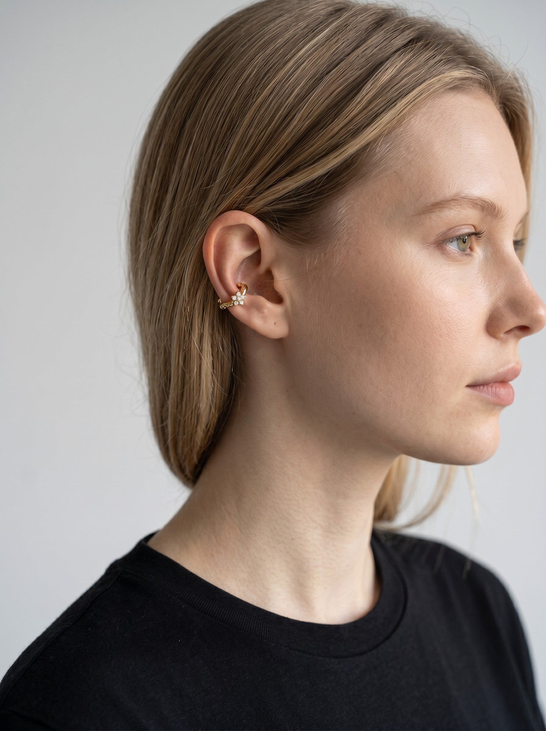Color's Wholesale gold ear cuff featuring a delicate flower design with small sparkling crystals on a model