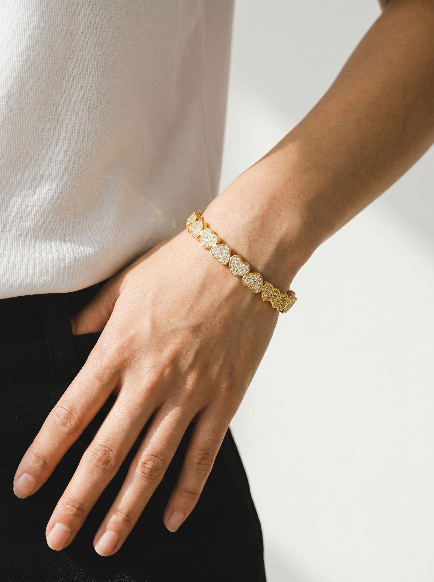 Color's Wholesale gold heart charm bracelet with sparkling crystals worn on a woman's wrist
