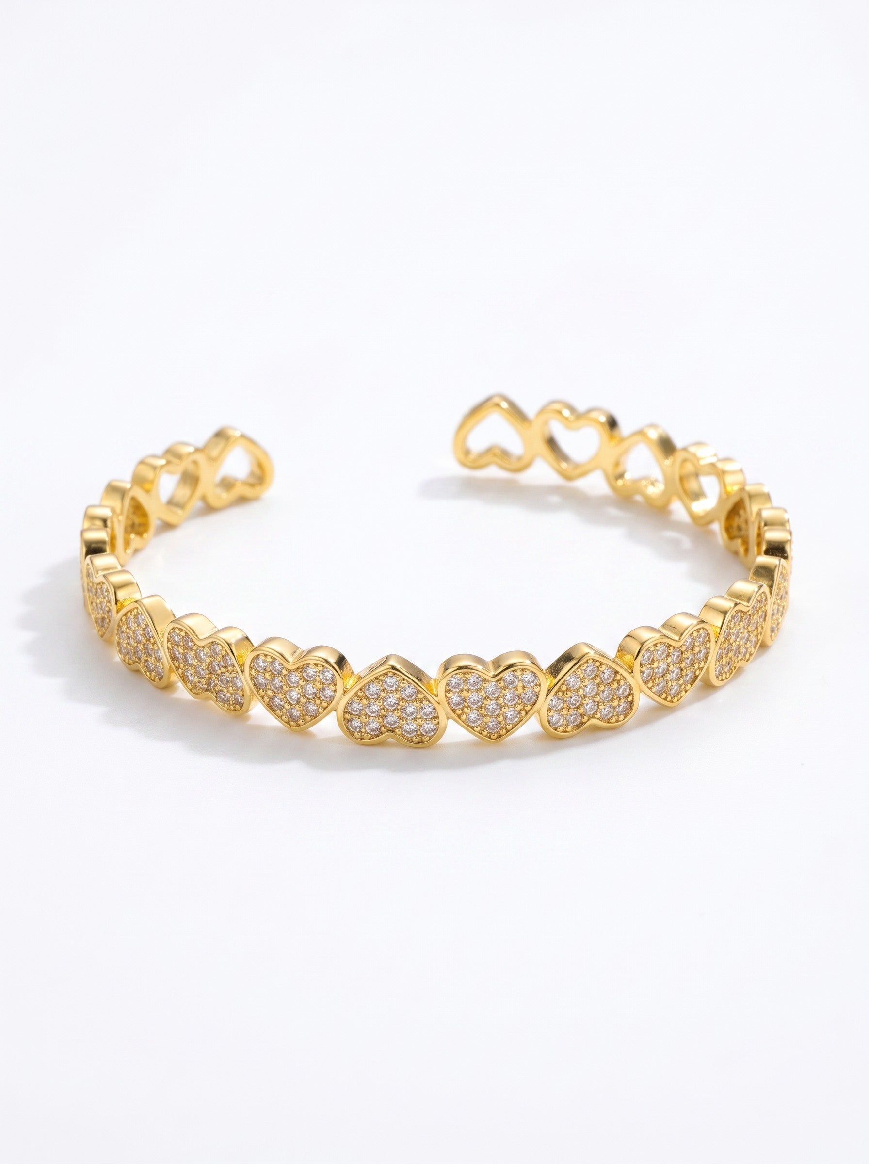 Color's Wholesale gold cuff bracelet featuring a continuous row of heart-shaped links encrusted with sparkling crystals.