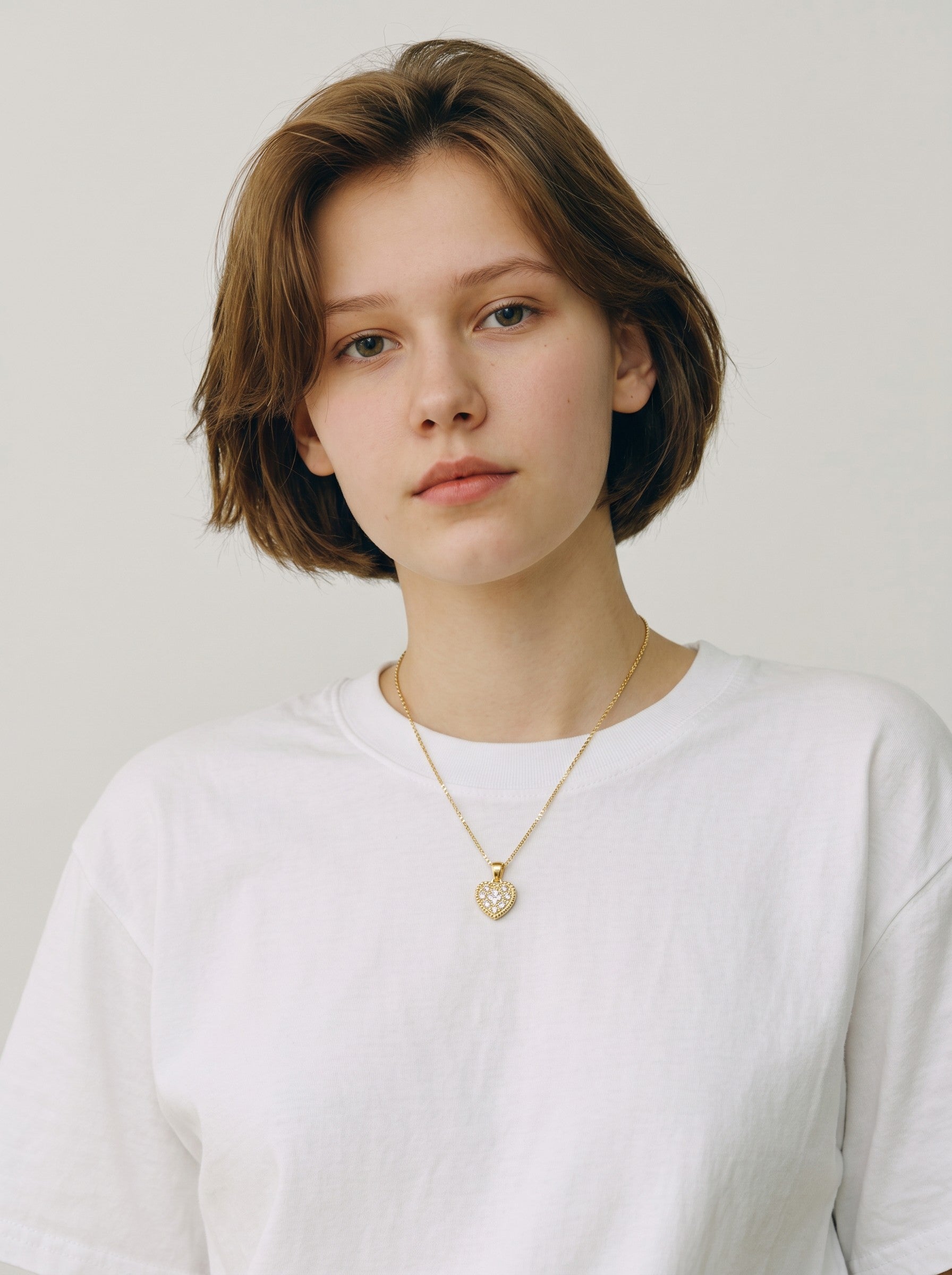 Model wearing a Color's Wholesale gold heart pendant necklace with crystal accents on a simple chain.