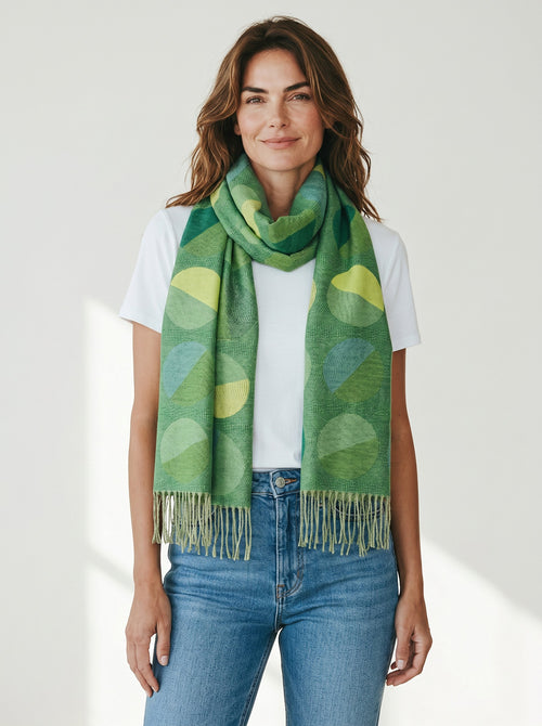 Woman wearing a Color's Wholesale green viscose scarf with a geometric circle pattern and fringe trim.