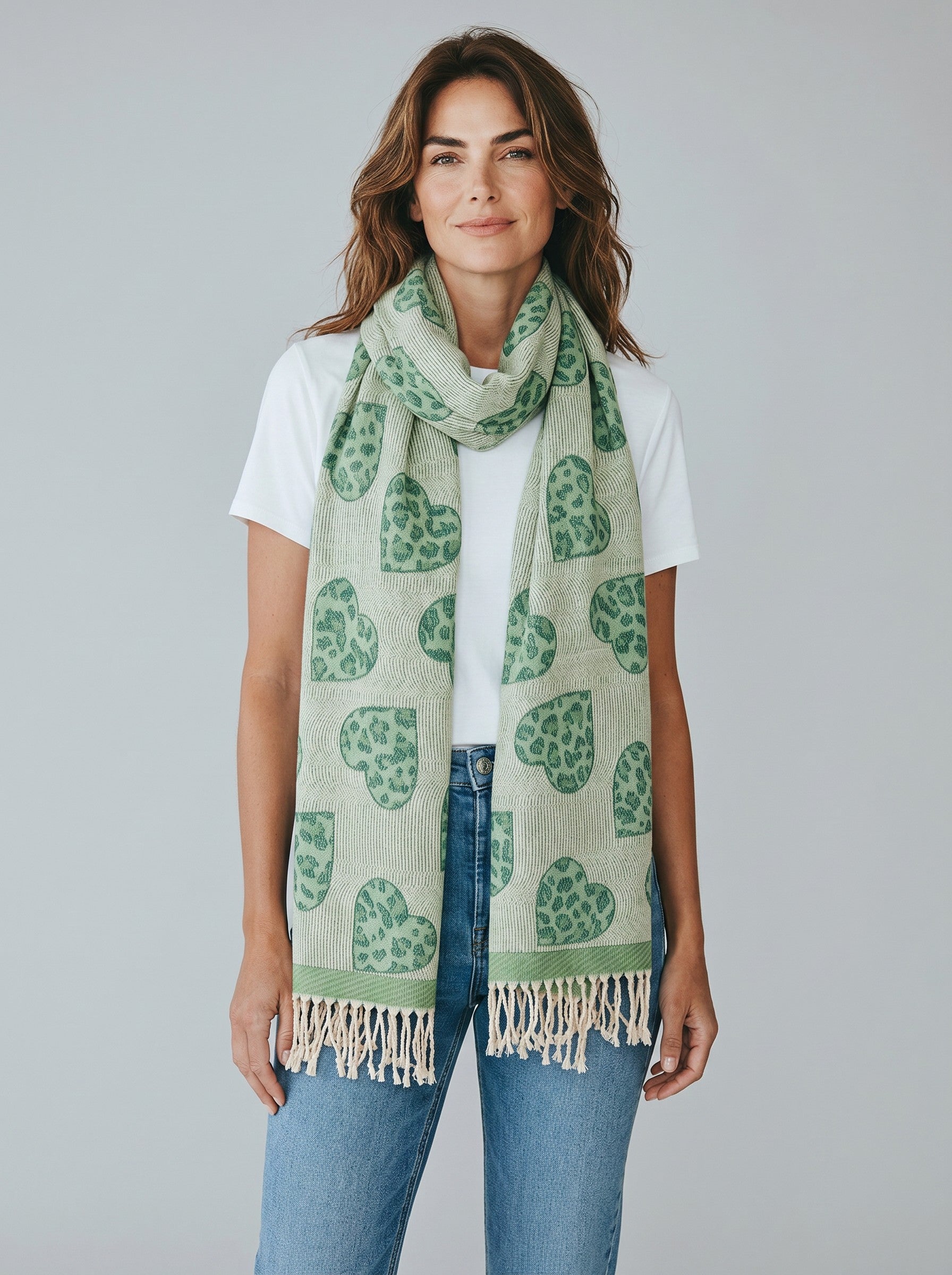 Model wearing a Color's Wholesale green viscose scarf featuring a leopard print heart pattern and tasseled ends.