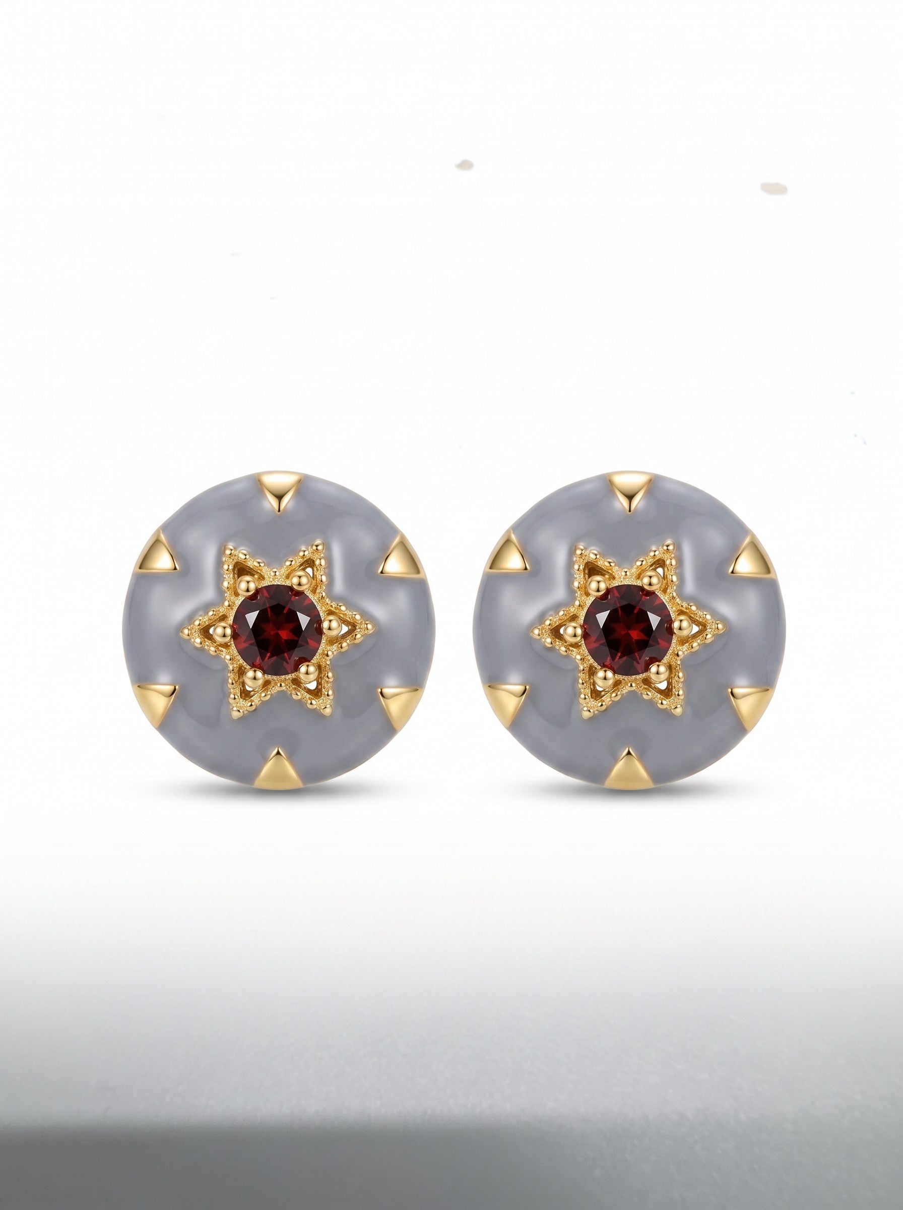 Color's Wholesale round stud earrings featuring grey enamel, gold star settings, and central deep red garnet stones.