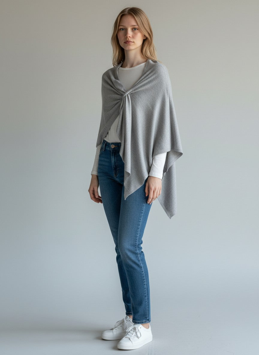 Color's Wholesale light grey knit poncho with a twisted knot detail and coral lining.