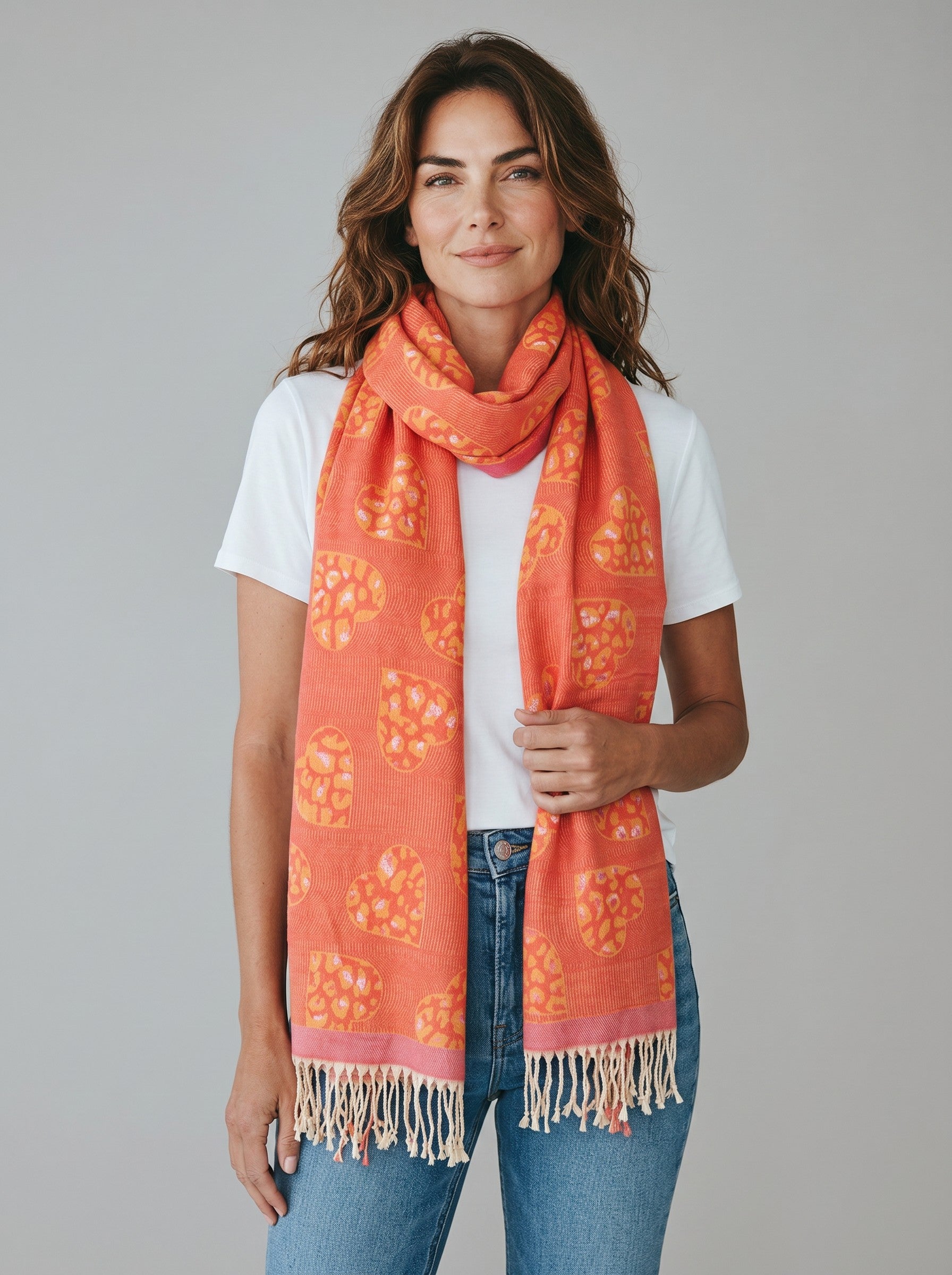 Color's Wholesale orange viscose scarf featuring a heart and leopard print pattern with fringed edges on a model.