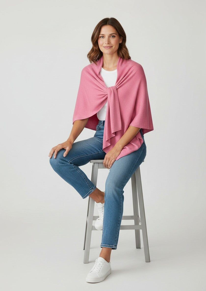 Color's Wholesale pink knit poncho with a twisted knot detail and asymmetrical hem.