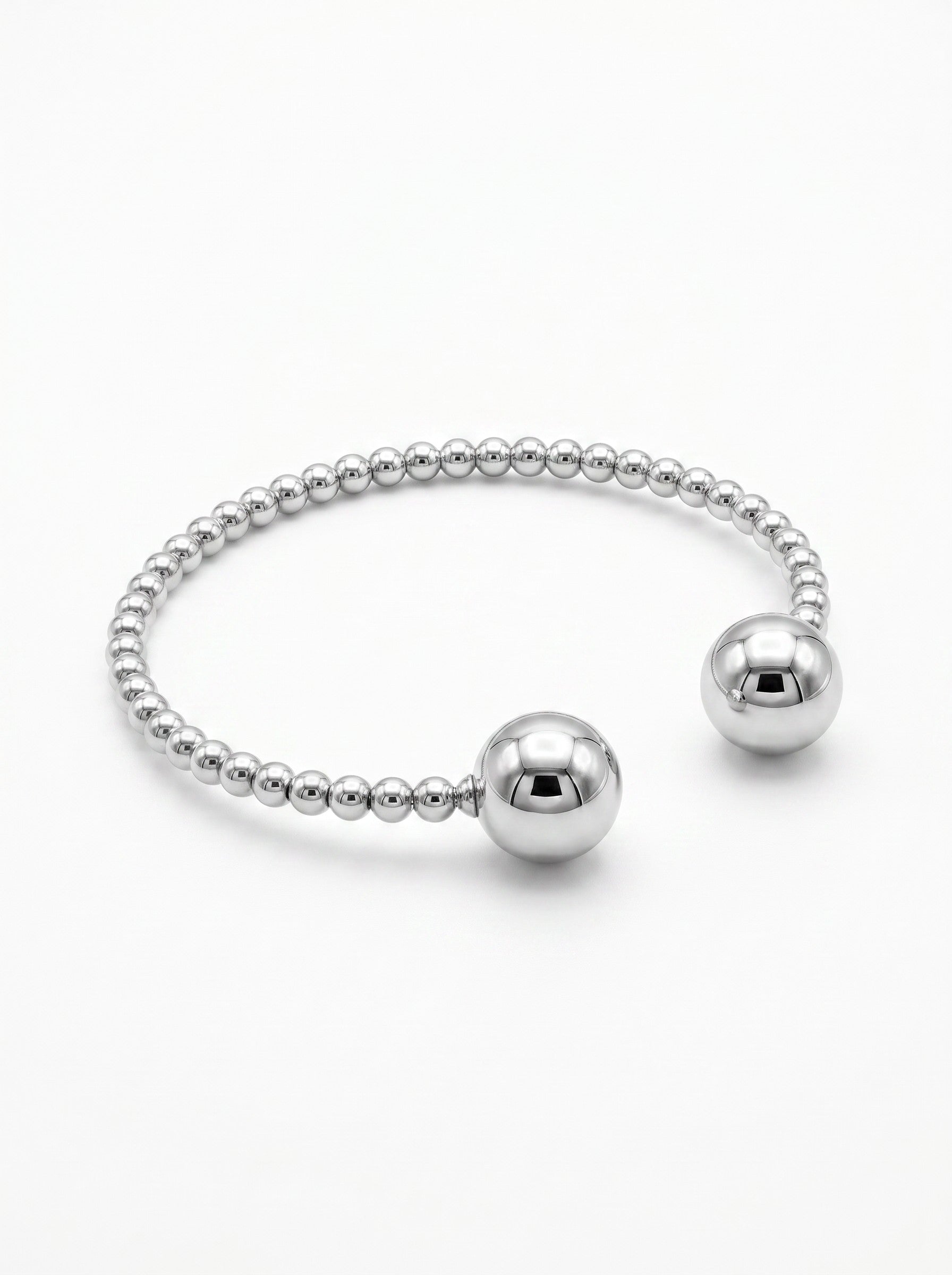 Color's Wholesale silver beaded cuff bracelet with two large polished spherical ends on a white background