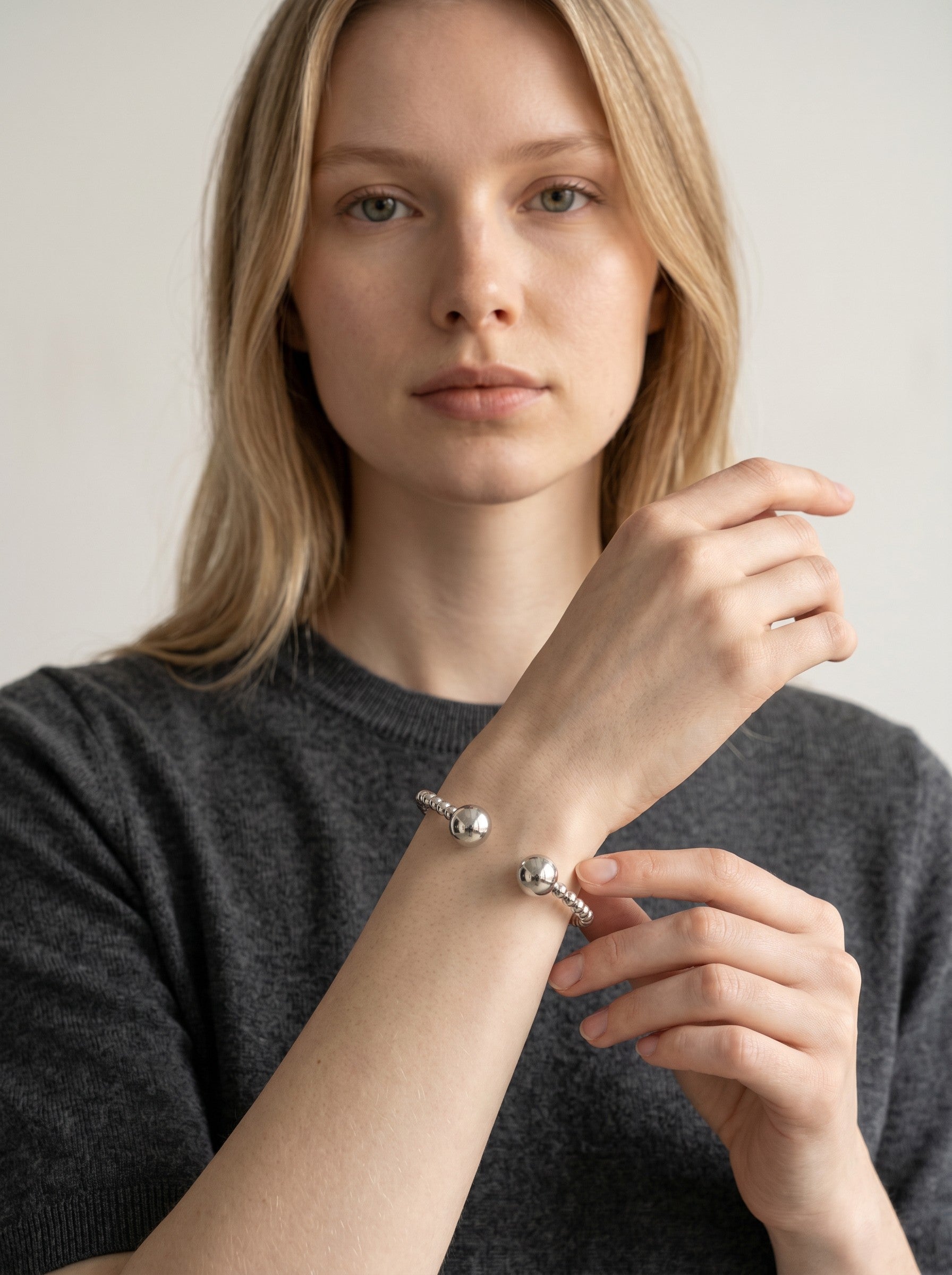 Color's Wholesale silver beaded cuff bracelet with large spherical ends worn on a model's wrist.