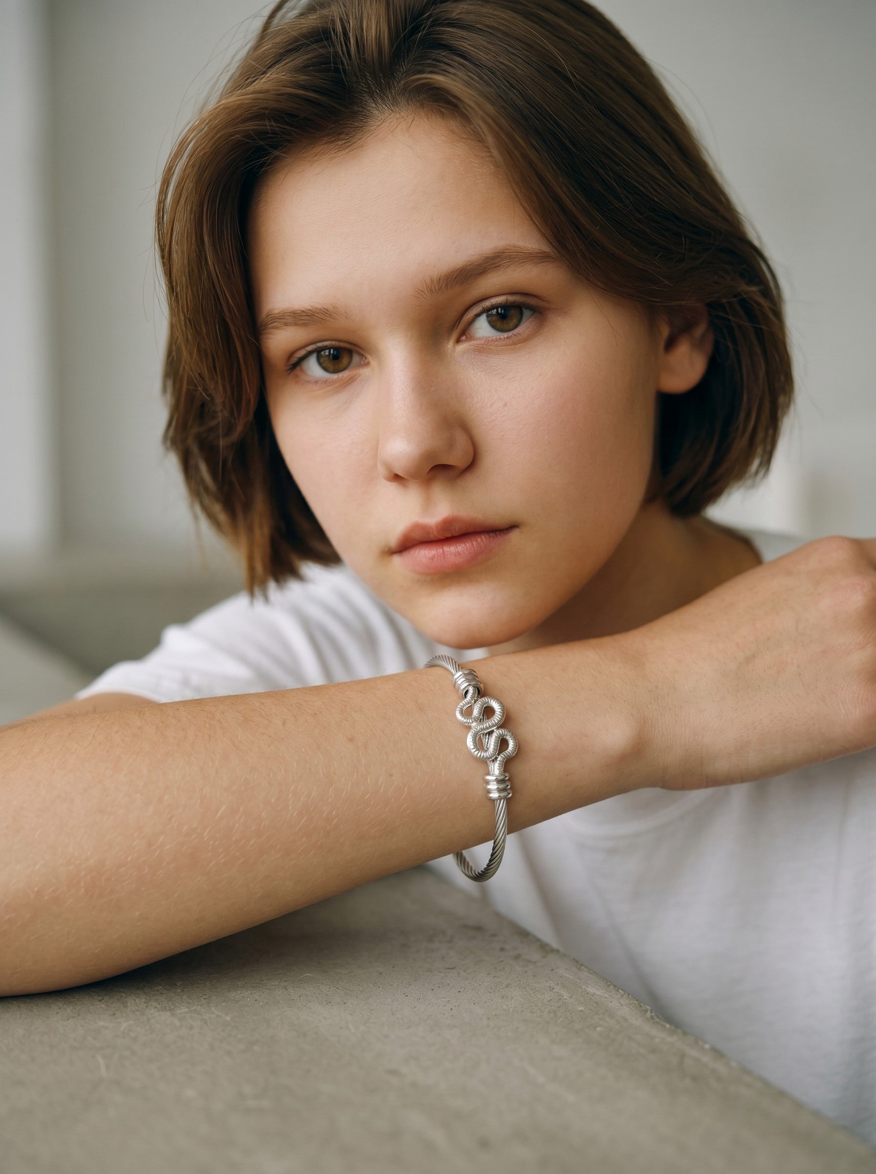Color's Wholesale silver twisted cable bracelet with heart charm worn by a young woman in a white t-shirt