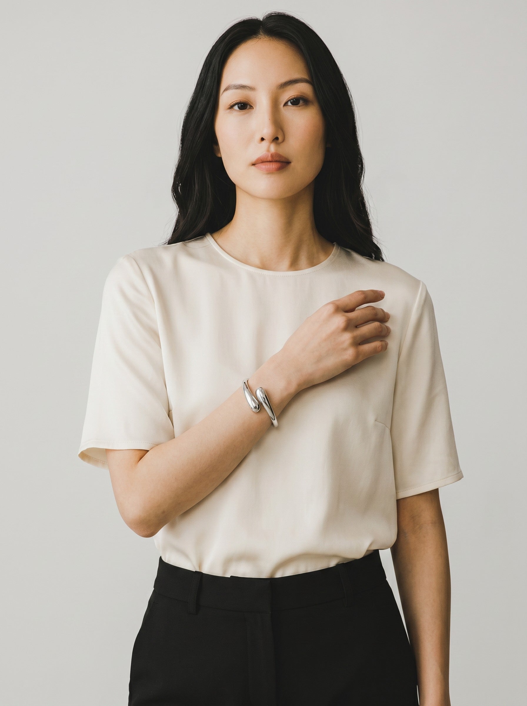 Color's Wholesale silver-toned metal cuff bracelet with a smooth, minimalist teardrop design worn by a woman.