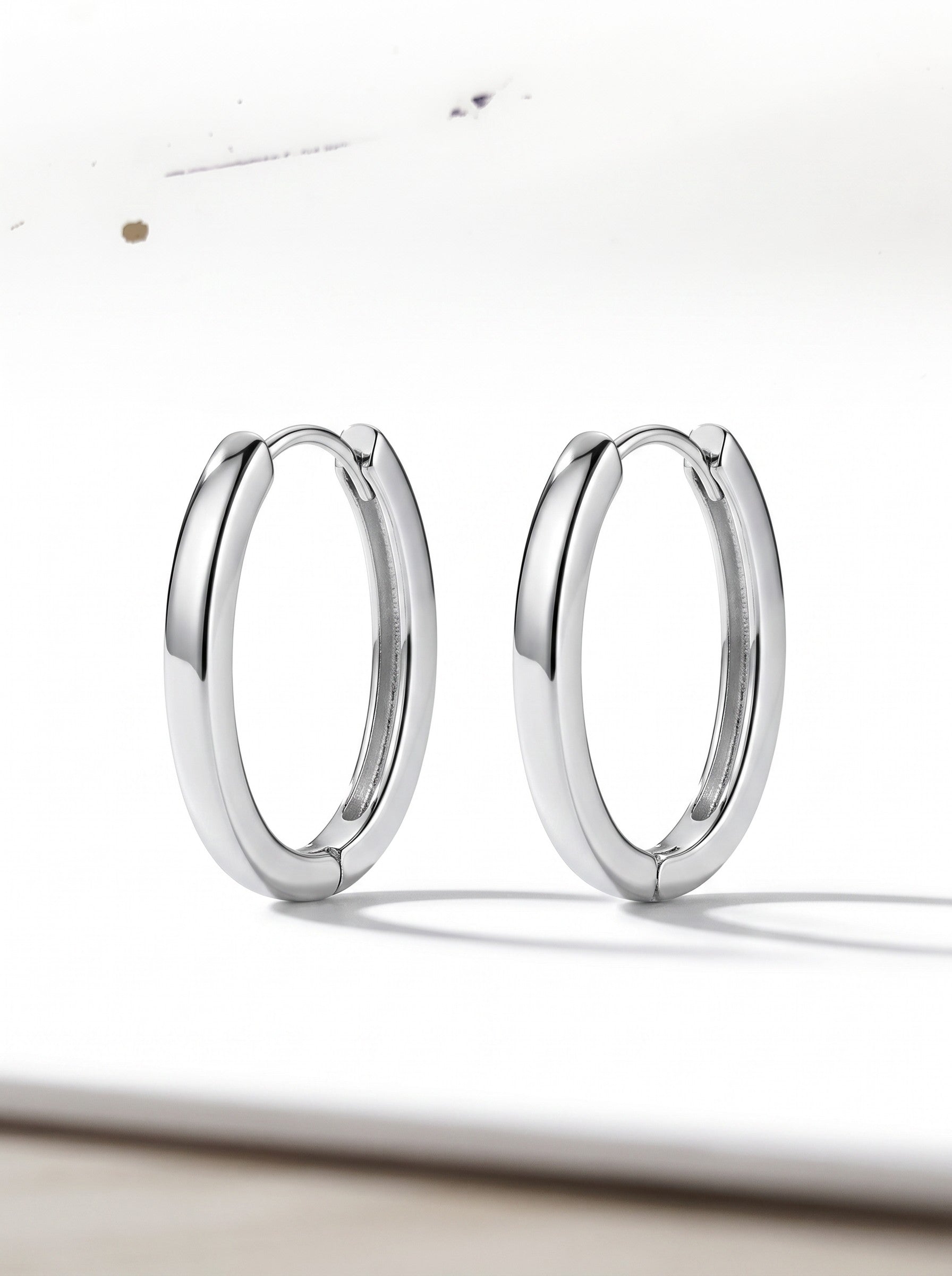 Color's Wholesale silver hoop earrings with a polished finish and secure hinged closure