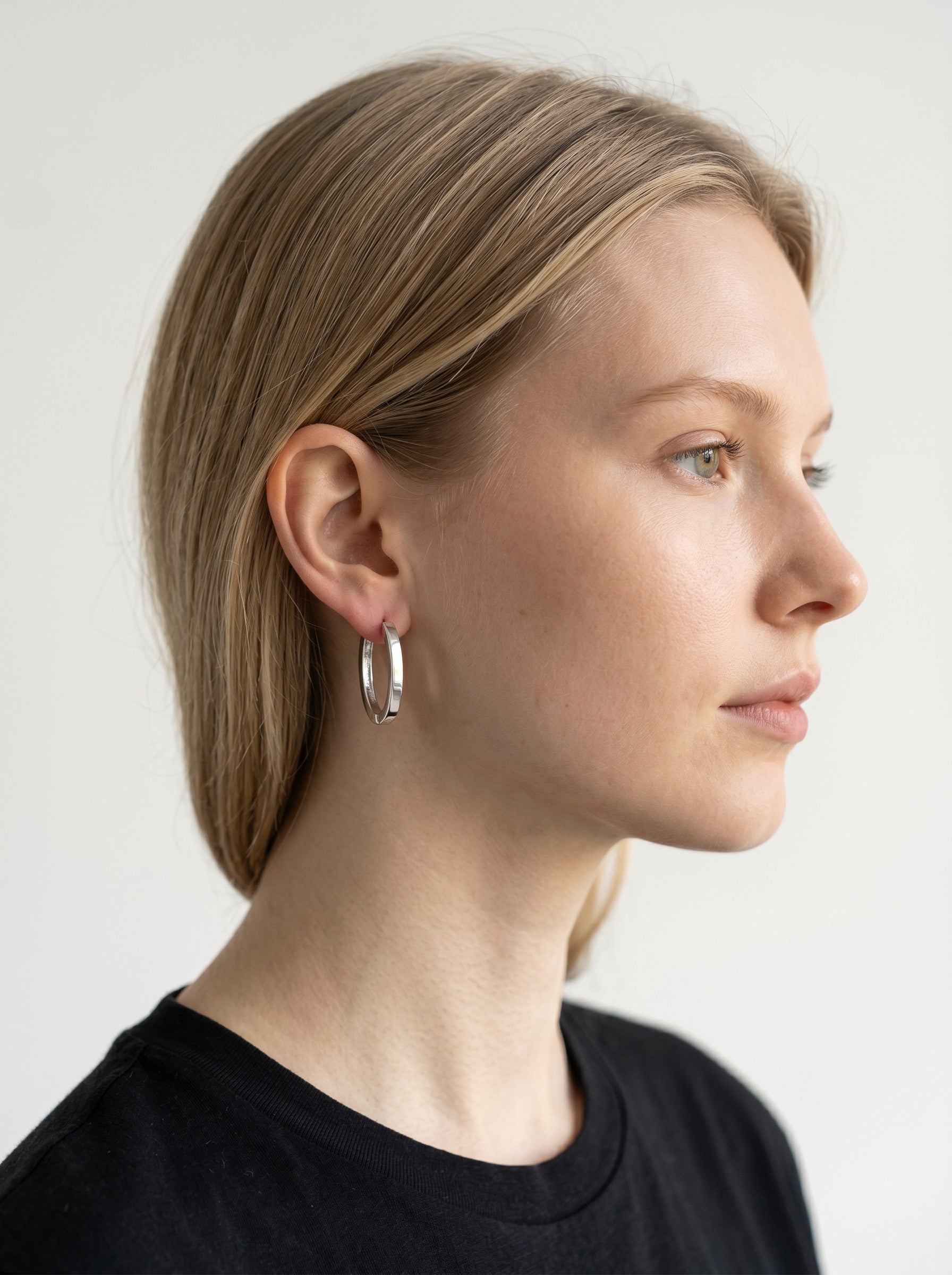 Color's Wholesale silver hoop earrings worn by a woman in profile view against a neutral background